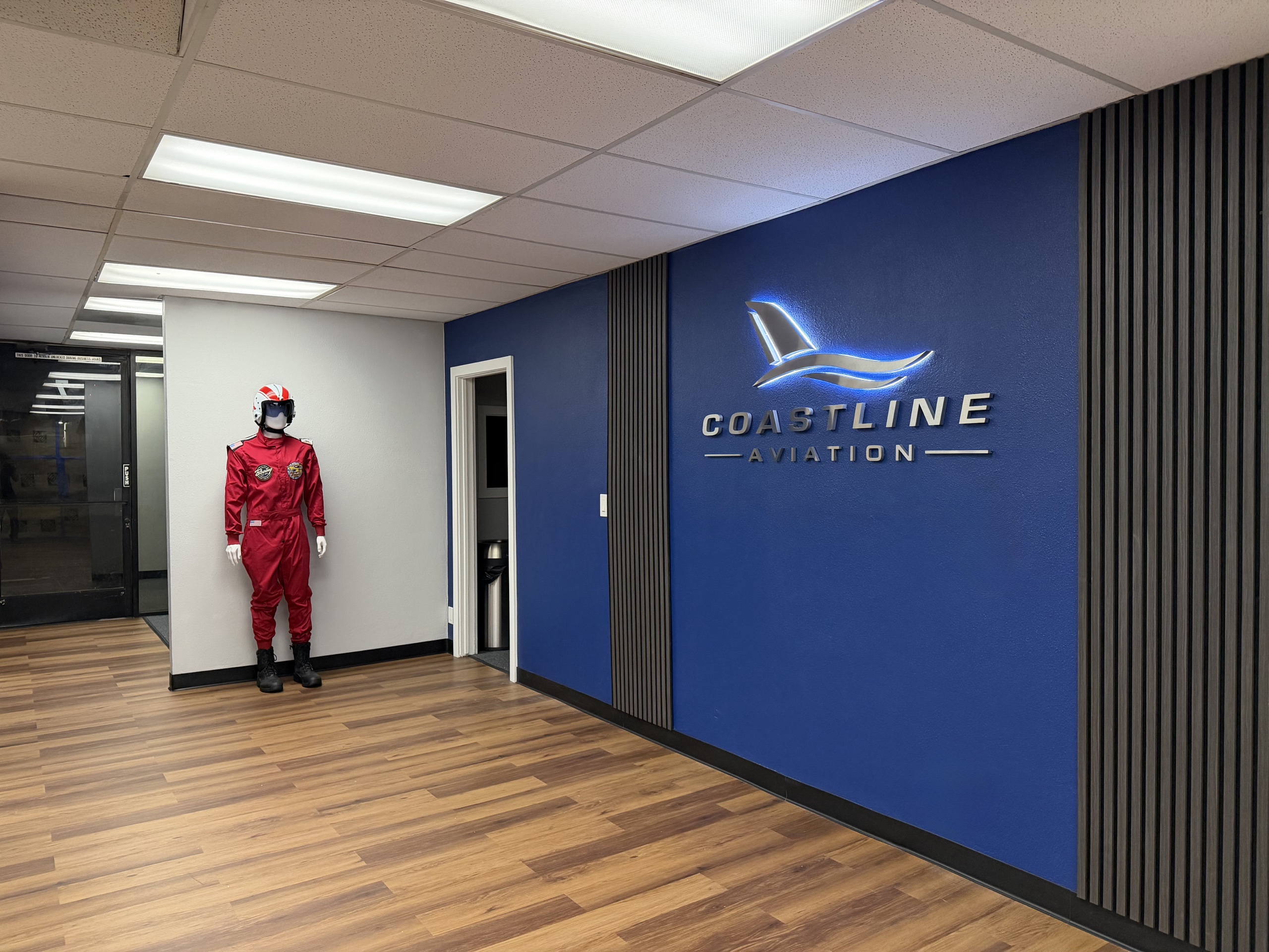 Backlit Coastline Aviation logo and dimensional letters on a blue lobby wall