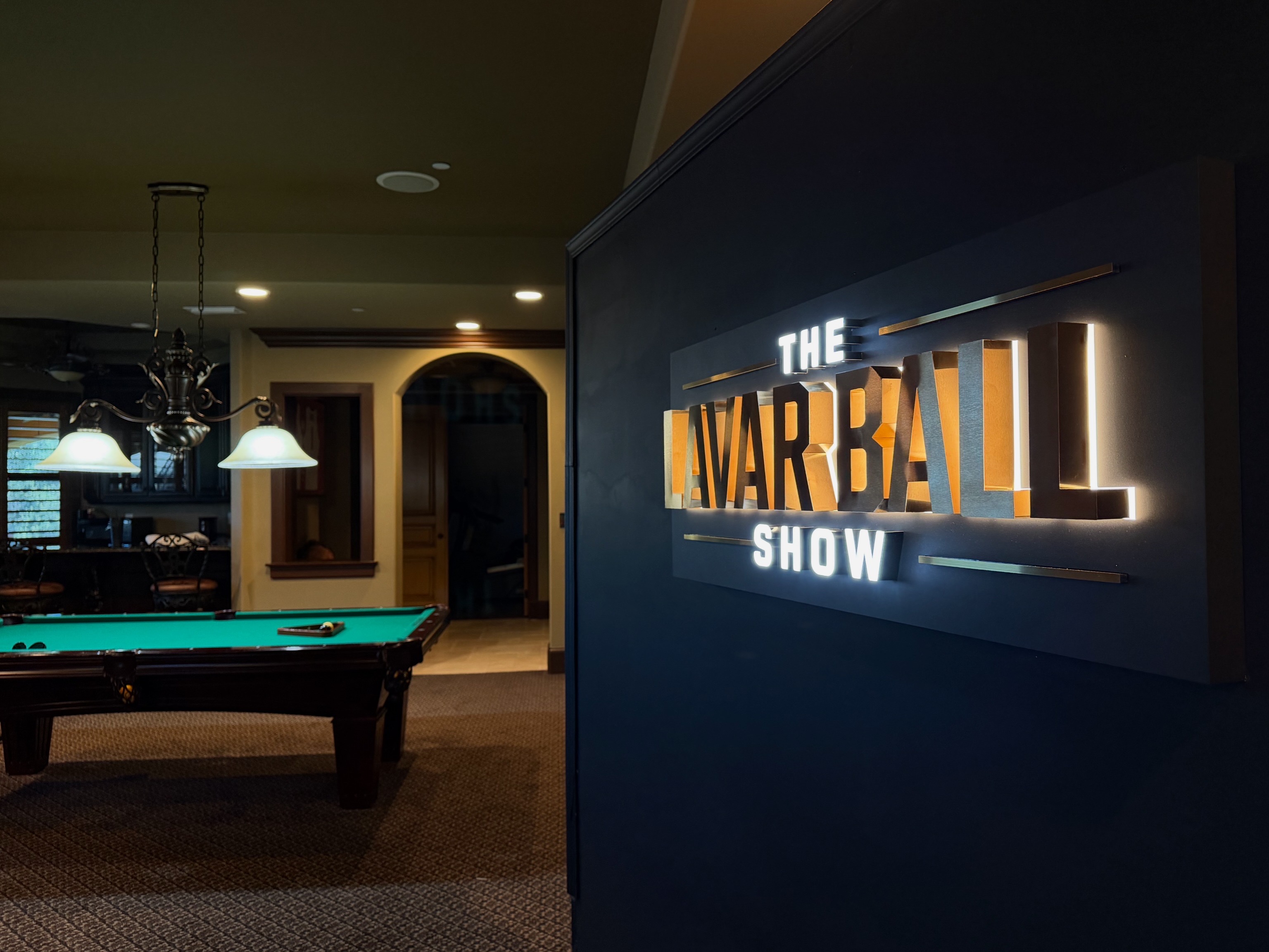 Illuminated sign for The Lavar Ball Show on a dark interior wall