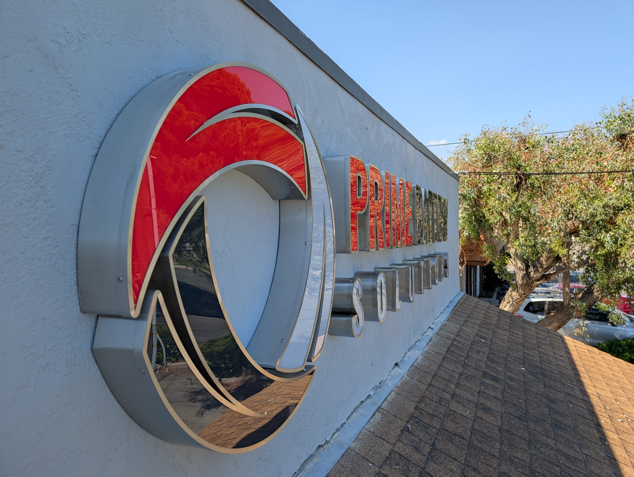 Red and metallic Prime Battery Solutions emblem and dimensional letters on an exterior wall